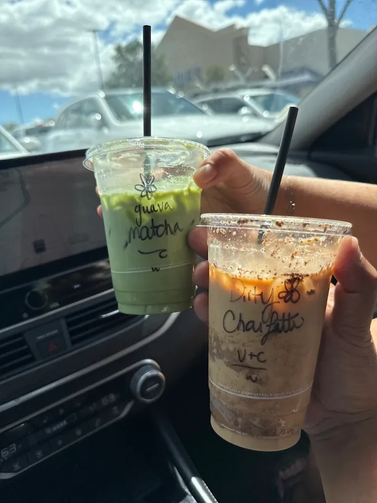 A guava matcha and a dirty chai latté held up inside a car.