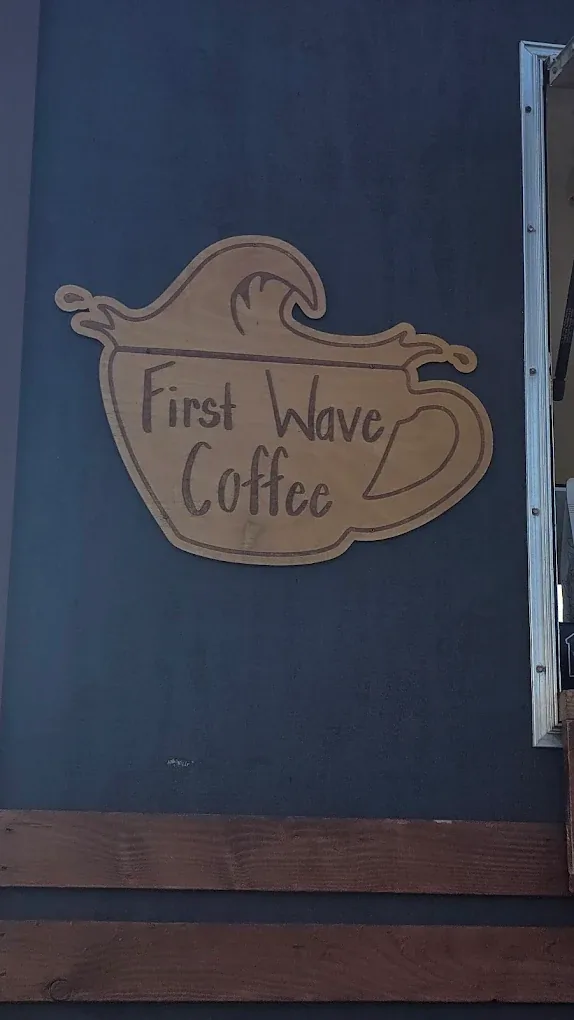 The hand-carved First Wave Coffee cup-and-wave logo mounted on the trailer.